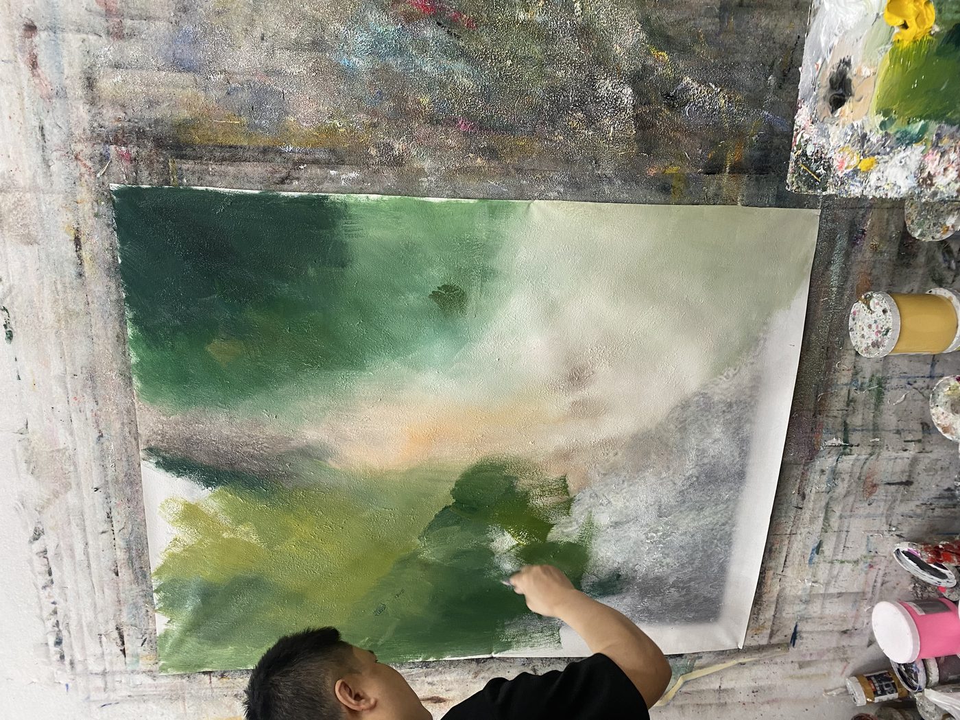 Dafen studio artist actively painting a green landscape, photographed from above