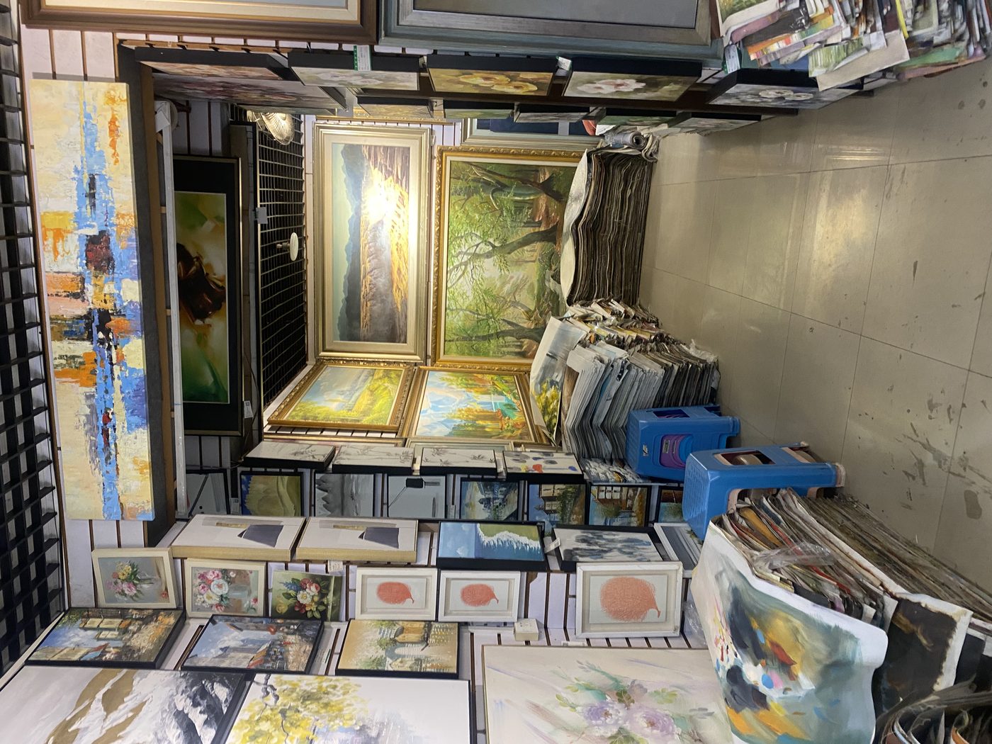 Paint cans and finished paintings side by side in our Dafen studio